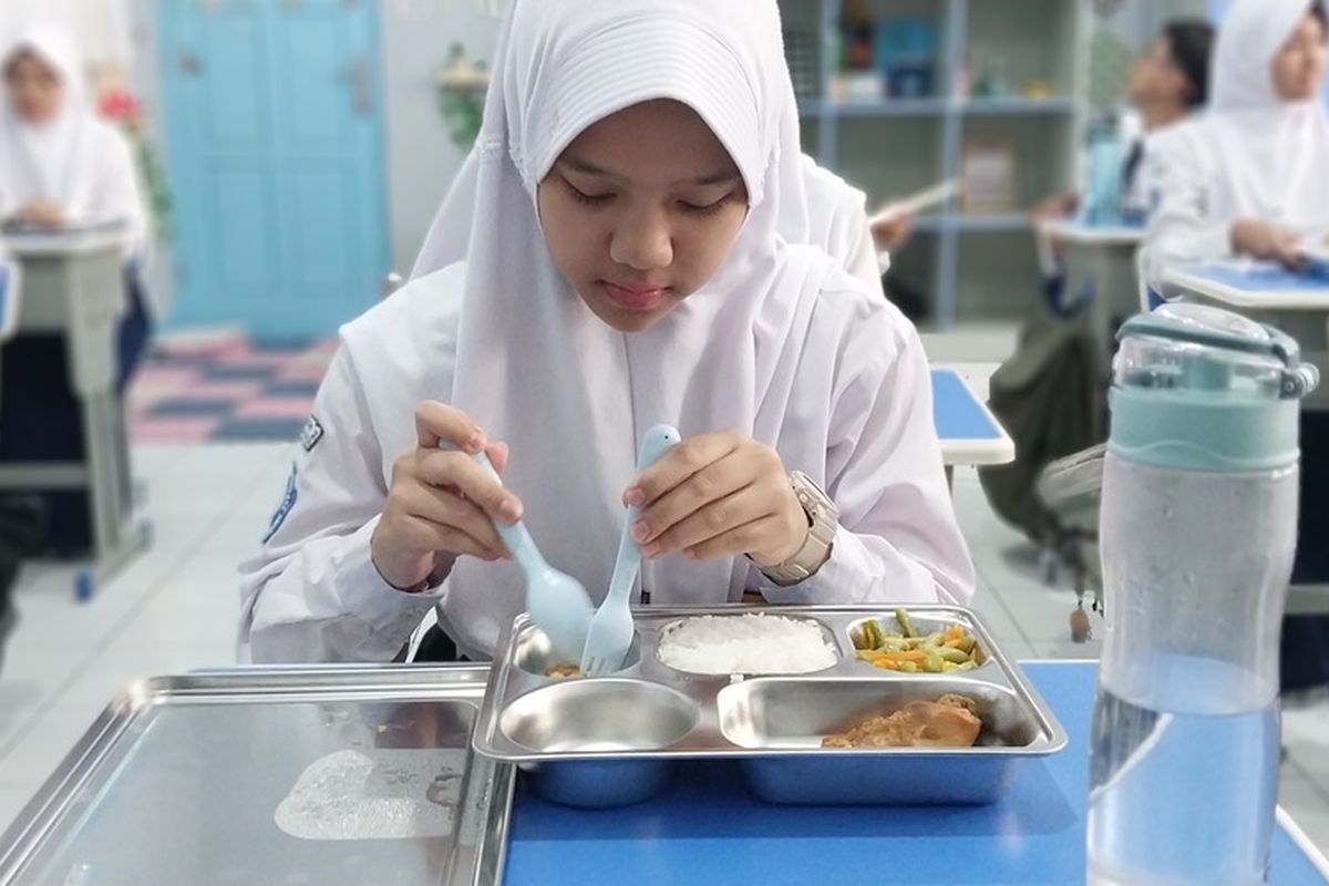 Pelajar SMPN 2 Tasikmalaya, Jawa Barat, sedang menyantap pembagian makan bergizi gratis dari pemerintah di ruang kelasnya pada Senin (6/1/2025) siang.
