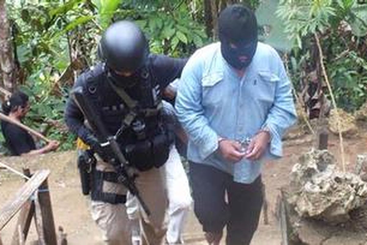 Salah satu terduga teroris yang sedang dibawa Tim Densus 88 Mabes Polri, usai melakukan penggeledahan terhadap barang bukti lainnya di kawasan Wailahan, Air Kuning Desa Batu Merah, Ambon. 