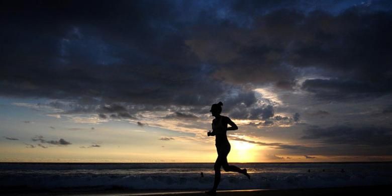 Seorang pelancong jogging di tepi pantai seiring terbenamnya matahari di anak-anak bermain-main di pantai saat senja di Seminyak, Bali, Sabtu (18/2/2017).
