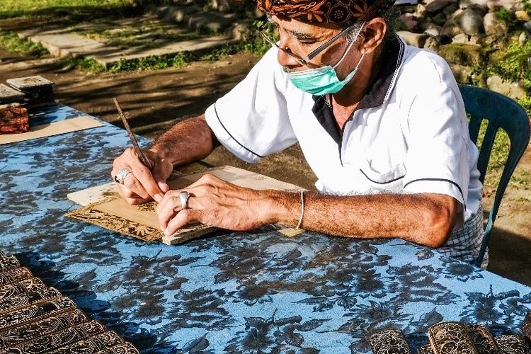 Pengrajin sedang membuat ukiran daun lontar. 