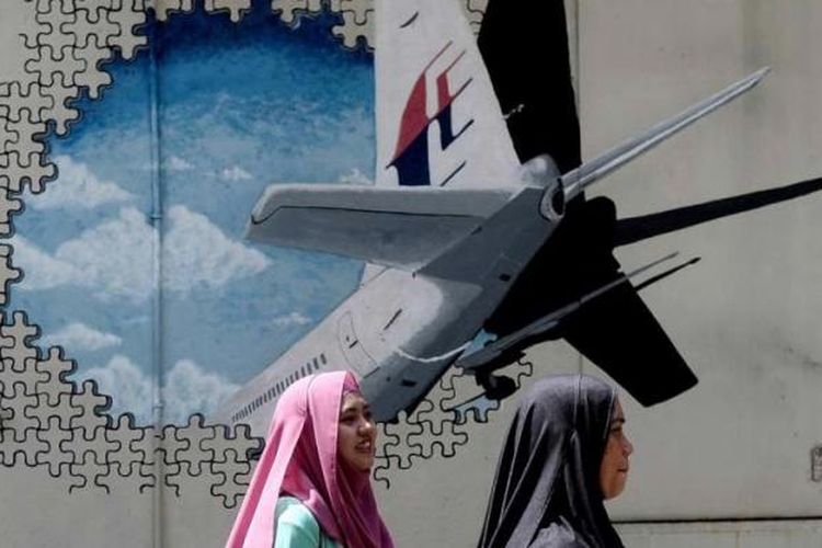 Dua warga melintas di depan mural hilangnya pesawat Malaysia Airlines MH370 di sebuah gang di Shah Alam, Malaysia, 8 Maret 2016.