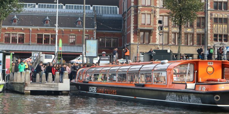 Penumpang mengantre sebelum menaiki kapal untuk tur menyusuri kanal di kota Amsterdam, Belanda.