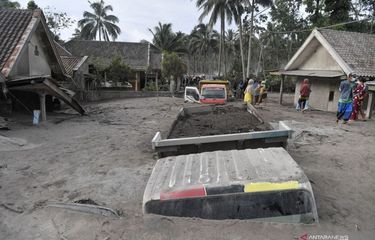 Warga mengamati truk pengangkut pasir yang tertimbun abu Gunung Semeru di Desa Sumberwuluh, Kabupaten Lumajang, Provinsi Jawa Timur, Minggu (5/12/2021).