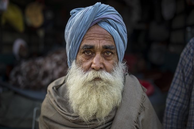 Jagtar Singh, 78, duduk untuk berfoto di belakang troli traktornya yang diparkir di jalan raya saat ia bergabung dengan petani lain yang memprotes undang-undang baru yang mereka katakan akan mengakibatkan eksploitasi oleh perusahaan, yang pada akhirnya membuat mereka tidak memiliki tanah, di negara bagian Delhi-Haryana perbatasan, India, Selasa, 1 Desember 2020.