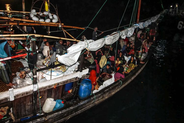 A group of over 100 Rohingya refugees sit in a boat as it arrives at an Indonesian port in North Aceh on Friday, Dec. 31, 2021. The Indonesian government allowed the refugees to berth in Aceh due to damaged engine. 