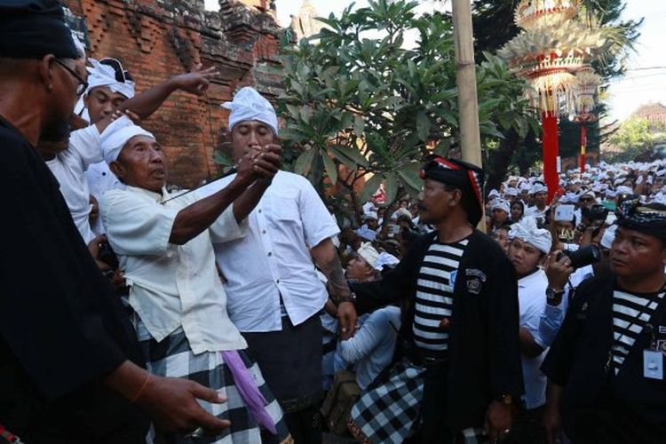 Pemedek dalam keadaan kesurupan (kerahuan) mengujamkan keris di dada (ngurek) dalam tradisi Ngerebong di Pura Dalam Petilan, Kesiman, Denpasar. Minggu (2/8/2015).