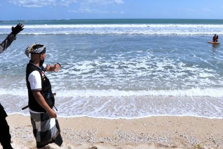 Polisi bersama Pecalang atau petugas keamanan adat Bali meminta wisatawan untuk meninggalkan kawasan wisata Pantai Kuta di Badung, Bali, Sabtu (03/07).