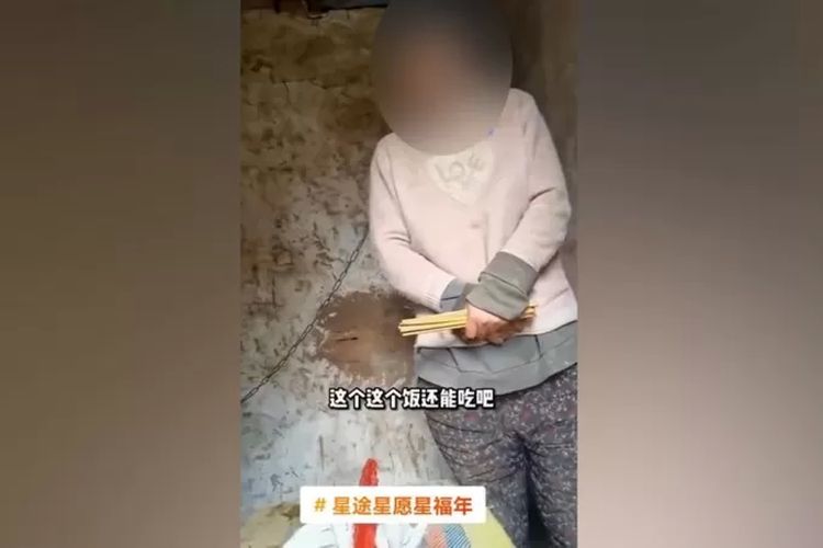 Gambar tampilan layar dari video yang viral menunjukkan seorang perempuan berdiri di gubuk dalam kondisi dirantai pada lehernya.