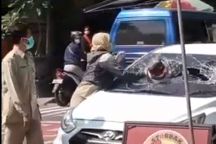 Viral beredar video berdurasi 8 detik yang menayangkan perempuan berseragam setelan coklat ASN di Kabupaten Ngawi memecahkan kaca sebuah mobil dengan helm yang dibawanya