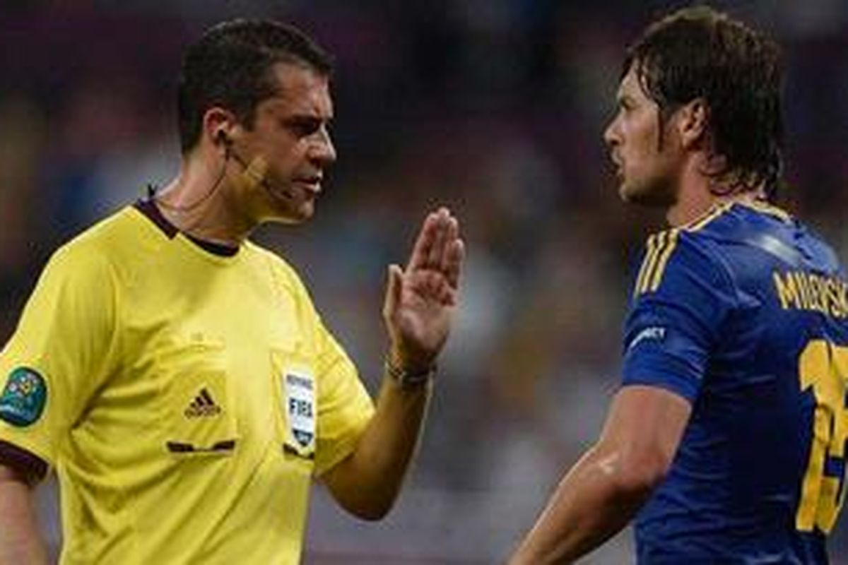 Wasit Hongaria, Viktor Kassai, menenangkan bomber Ukraina Artem Milevskiy dalam pertandingan melawan Inggris di Stadion Donbass Arena, Donetsk, Selasa (19/6/2012). Inggris menang lewat gol tunggal Wayne Rooney. Kassai kembali ditugaskan UEFA untuk memimpin laga kedua 16 besar Liga Champions antara Barcelona versus AC Milan.