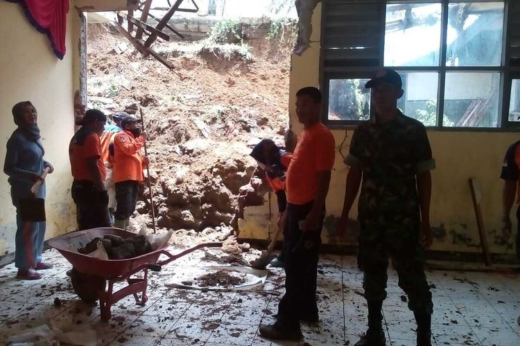 Anggota BPBD dan TNI Koramil Salopa sedang membersihkan material longsoran tanah yang menimbun bangunan kelas SMPN 3 Jatiawaras Kabupaten Tasikmalaya, Minggu (16/2/2020).