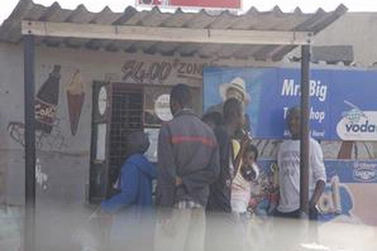 Inilah salah satu kawasan kumuh di Soweto, dekat Johannesburg, sekaligus daerah paling berbaya. Tampak para penghuni kawasan kumuh sedang antre telepon koin yang sudah makin langka di Afsel.