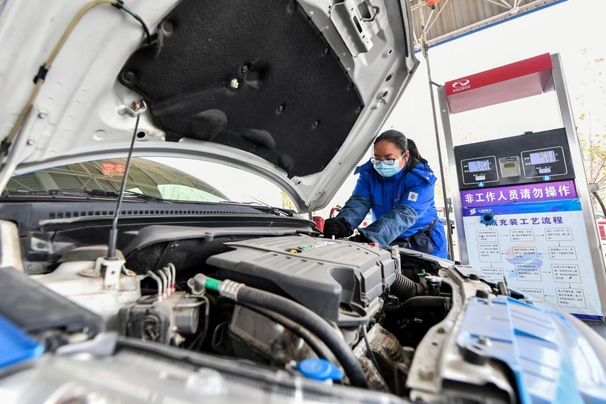 Foto menunjukkan seorang pekerja sedang mengisi bahan bakar sebuah mobil dengan gas batu bara (coal seam gas) di stasiun pengisian bahan bakar di kota Jincheng, provinsi Shanxi, China utara, pada 9 Desember 2020. Para personel yang melakukan kontak langsung dengan barang-barang itu telah dikarantina dan semua tes mereka dinyatakan negatif Covid-19. Barang-barang tersebut juga telah disegel.