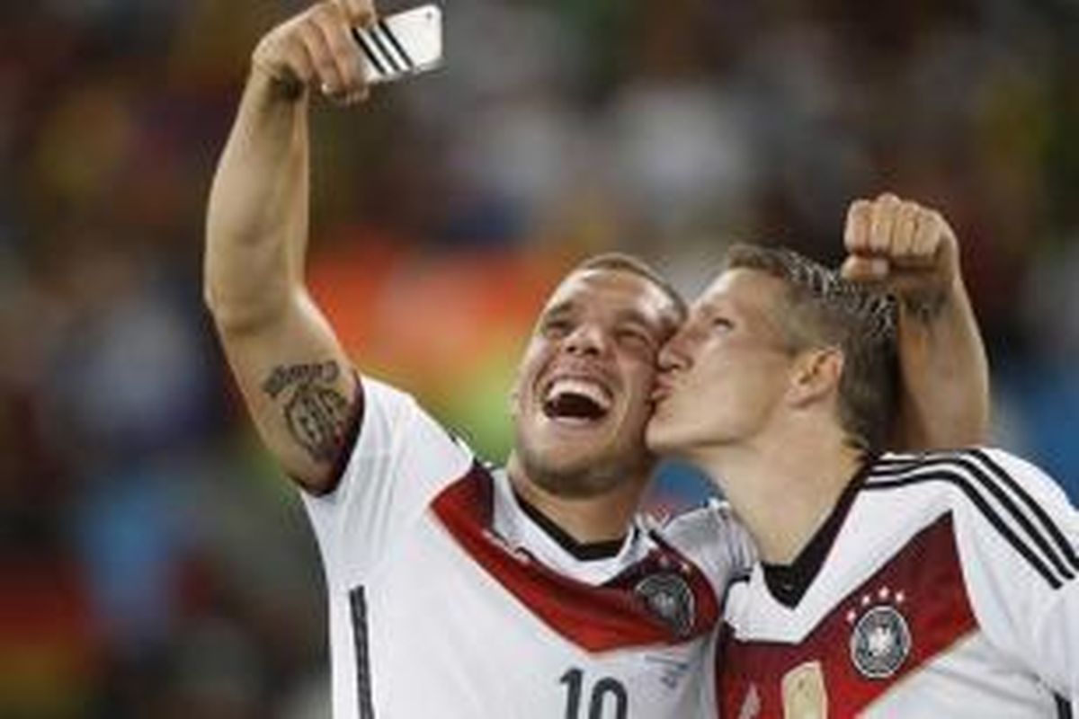 Pemain Jerman Bastian Schweinsteiger (kanan) dan Lukas Podolski membuat foto 'selfie' setelah memenangkan laga Final Piala Dunia melawan Argentina di Maracan Stadium, Rio de Janeiro, 13 Juli 2014. Jerman menang dengan sko 1-0.