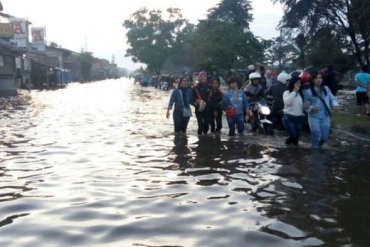 Sejumlah karyawan pabrik di wilayah Cimanggung terlihat tengah berjuang melintasi banjir di Jalan Raya Bandung-Garut dengan berjalan kaki, Minggu (12/3/2017). 