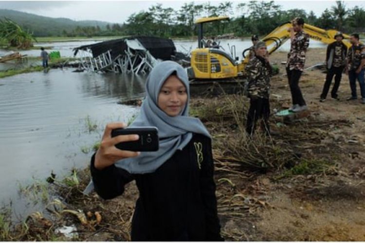 Seorang perempuan muda mengambil swafoto di lokasi bencana tsunami, di Banten.