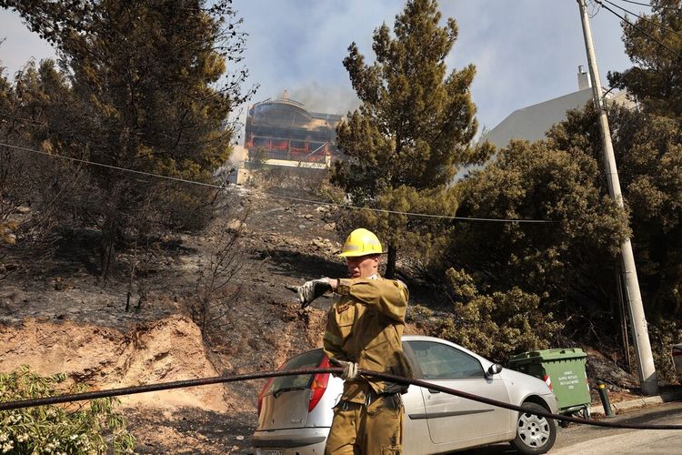 Api melalap sebuah rumah saat relawan pemadam kebakaran beroperasi saat kebakaran hutan di pinggiran Voula, di selatan Athena, Yunani, Sabtu, 4 Juni 2022. 