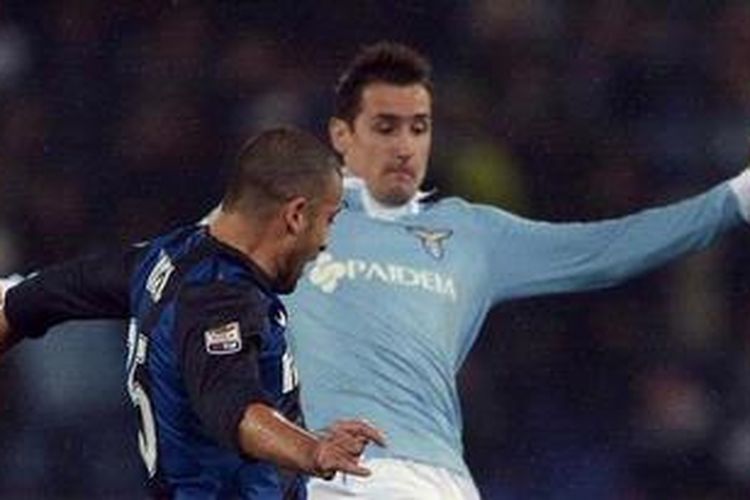 Penyerang Lazio, Miroslav Klose, berebut bola dengan bek Inter Milan, dalam lanjutan Serie-A, sabtu (15/12/2012). 