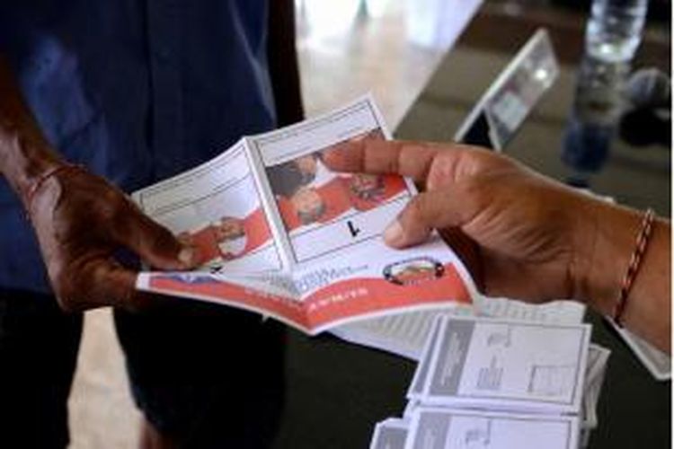 Petugas pemungutan suara memberikan surat suara kepada pemilih di tempat pemungutan suara di Kuta, Bali, 9 Desember 2015. 100 juta pemilih hari ini memberikan suara untuk pemilihan kepala daerah yang dilakukan serentak di 32 provinsi untuk pertama kalinya.