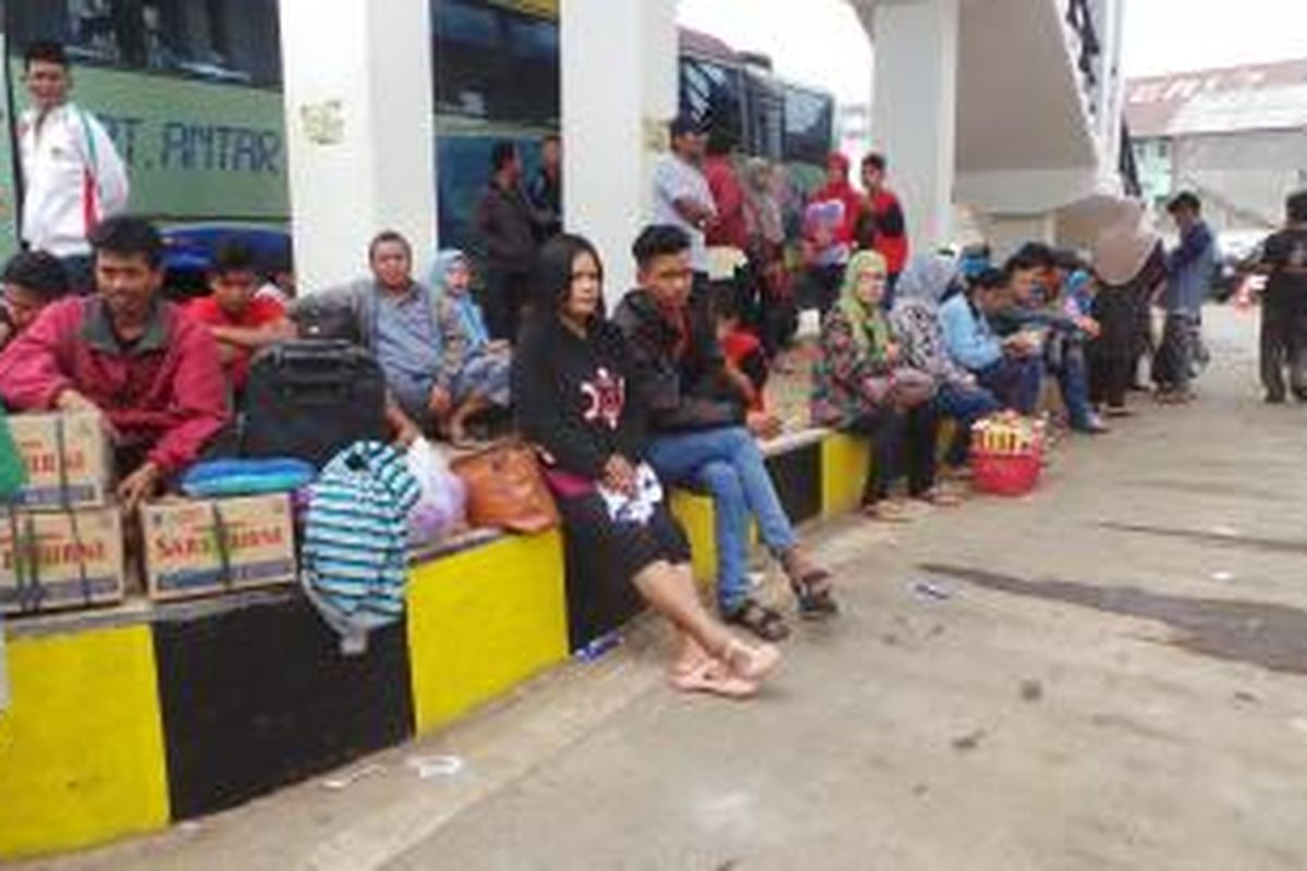 Puluhan penumpang bus di Terminal Rambutan, Jakarta Timur. Para penumpang ini terpaksa duduk di trotoar karena ruang tunggu terminal yang belum dioperasikan. Selasa (7/7/2015).