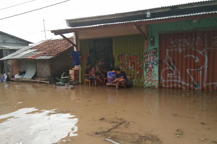 Sejumlah warga tengah duduk di rumah yang terdampak banjir di Dusun Pengasinan Desa Karangligar, Kecamatan Telukjambe Barat, Kabupaten Karawang, Rabu (1/1/2019).