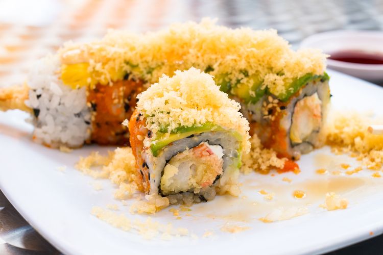 Ilustrasi sushi dengan taburan tempura flakes di atasnya. 