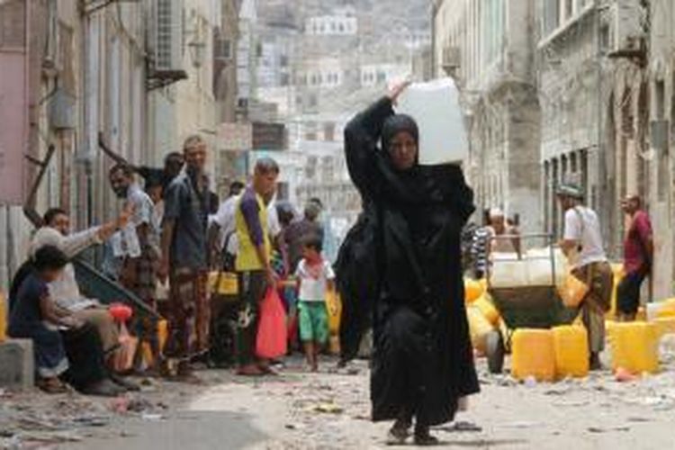 Seorang perempuan memanggul air bersih di salah satu kota Aden, Yaman yang hancur akibat perang. Jutaan warga Yaman membutuhkan bantuan kemanusiaan setelah terjebak dalam perang antara pemberontak Houthi dan pasukan loyalis pemerintah.