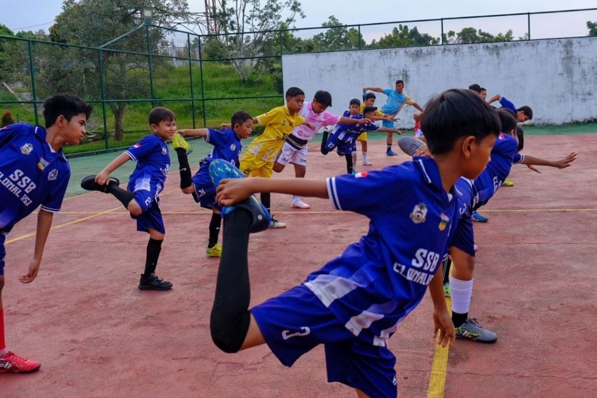 Anak-anak SSB Kolonal melakukan peregangan sebelum memulai sesi latihan sepak bola.