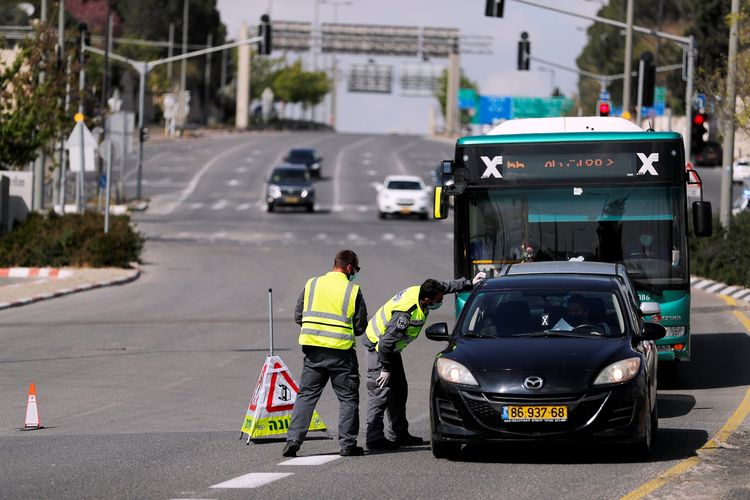 Polisi Israel melakukan pengecekan pada seorang pengendara mobil saat penutupan jalan utama, dalam upaya menahan penyebaran virus corona. Foto diambil pada 12 April 2020.