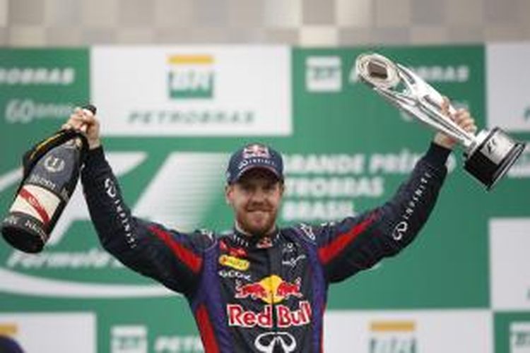 Pebalap Red Bull Racing asal Jerman, Sebastian Vettel mengangkat trofi, merayakan kemenangannya pada GP Brasil di Sirkuit Interlagos, Sao Paulo, Minggu (24/11/2013).