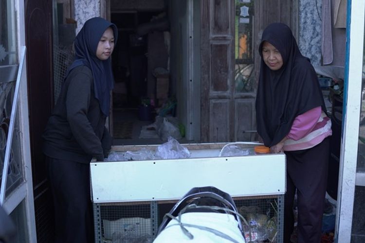 Terlihat, Linggas, remaja putri penerima manfaat Program Beasiswa YES yang diterima kuliah di Institut Teknologi Sepuluh Nopember (ITS), Surabaya. Ia sedang membantu ibunya mempersiapkan meja dan menata semua sayur dan bahan lainnya untuk dijual di depan rumahnya.