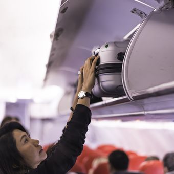 Penumpang menempatkan tas di kompartemen kabin pesawat. 