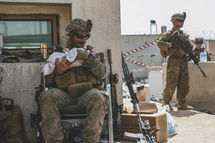 Foto dari Marinir Amerika Serikat memperlihatkan seorang prajuritnya di Unit Ekspedisi Laut (MEU) ke-24, menggendong bayi dan menenangkannya saat evakuasi penduduk dilakukan di bandara internasional Hamid Karzai, Kabul, Afghanistan, Jumat (20/8/2021).