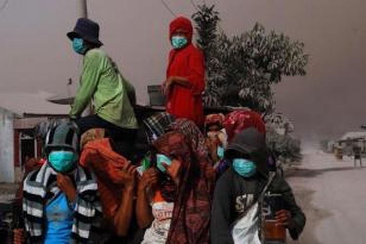Warga mengenakan masker untuk melindungi dari debu letusan Gunung Sinabung di Karo, Sumatera Utara, Kamis (9/10/2014). Letusan gunung ini telah menewaskan 17 orang.