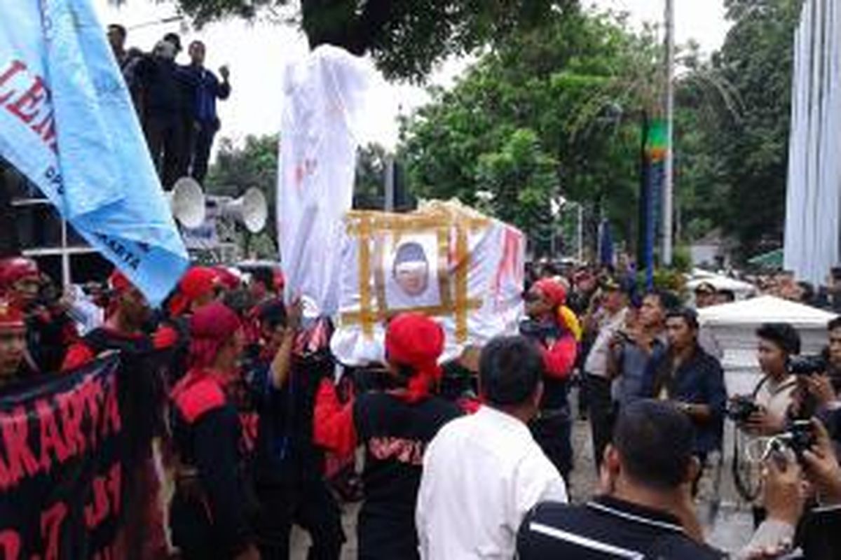 Massa buruh mengusung kardus menyerupai keranda yang ditempeli foto Gubernur DKI Jakarta Basuki Tjahaja Purnama saat berdemonstrasi di Balaikota DKI Jakarta, Rabu (26/11/2014).