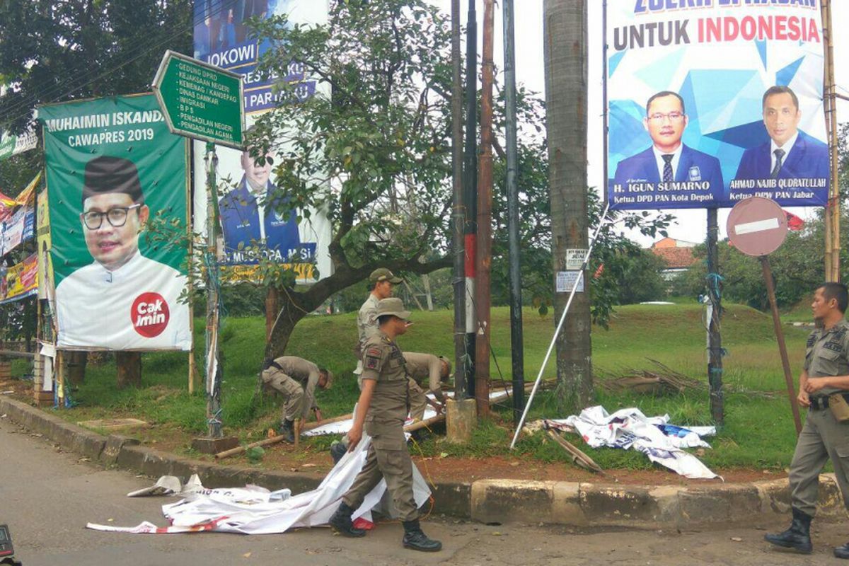 Satpol PP membongkar alat peraga kampanye yang terdapat di Jalan Boulevard Grand Depok City, Rabu (14/2/2018).