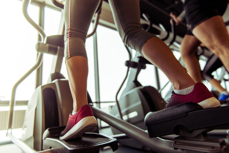 Ilustrasi pemula menggunakan elliptical trainer di tempat gym.