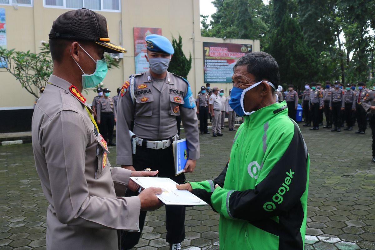 Kapolresta Banyumas Kombes Whisnu Caraka memberikan santunan kepada Mulyono, pengemudi ojol yang menjadi korban penipuan di halaman Mapolresta Banyumas, Jawa Tengah, Selasa (7/4/2020).