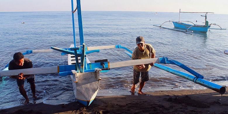 Nakhoda dibantu rekannya mendaratkan perahu jukung seusai mengantarkan wisatawan melihat lumba-lumba.