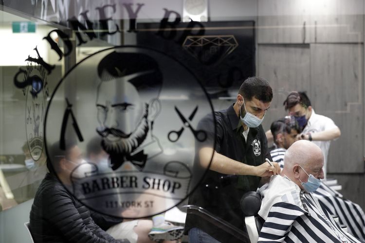 Sebuah barber shop di Sydney memotong rambut beberapa pelanggan pertama mereka setelah lebih dari 100 hari tutup karena lockdown untuk membantu mengatasi wabah Covid-19. [AP Photo/Rick Rycroft]