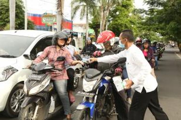 Pegawai Humas Pemkab Banyuwangi membagikan masker kepada pengendara motor yang melintas di halaman Pemda Banyuwangi