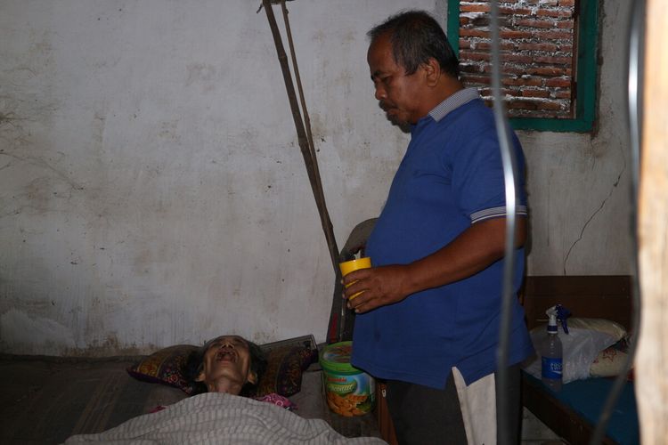 Koestomo (59), telaten merawat istrinya yang mengalami sakit dan lumpuh sejak 19 tahun lalu. Bersama keluarganya, tukang sepatu ini tinggal di Dusun Bandung Krajan, Desa Bandung, Kecamatan Diwek, Kabupaten Jombang, Jawa Timur.