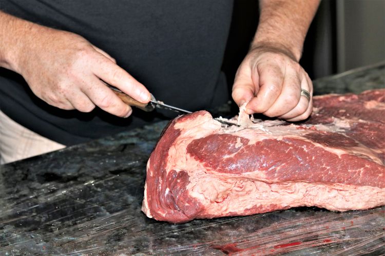 Ilustrasi proses memotong lemak atau trimming pada daging sapi bagian brisket. 