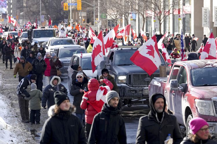 Truk dan pendukung berjalan di Bloor Street selama demonstrasi mendukung konvoi pengemudi truk di Ottawa memprotes pembatasan COVID-19, di Toronto, Sabtu, 5 Februari 2022. 
