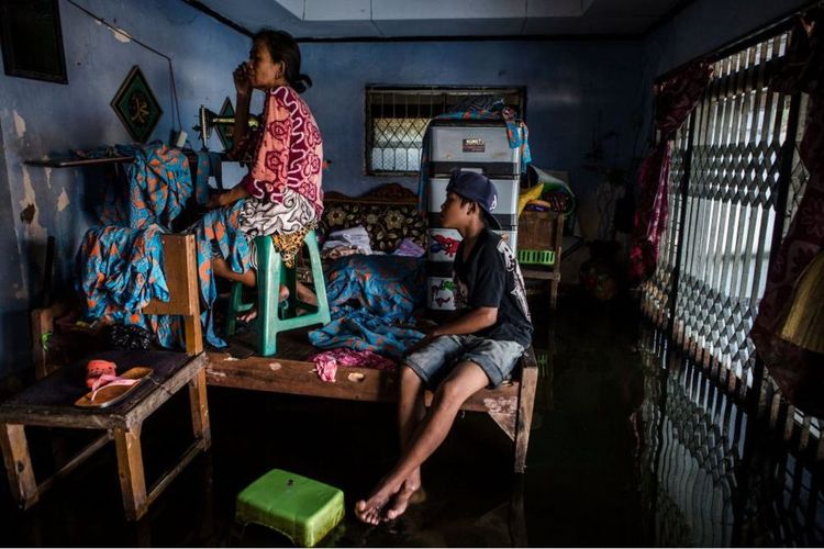 Bawon, seorang warga Pekalongan, beradaptasi dengan banjir laut yang melanda tiap tahun dengan beraktivitas di atas dipan tempat tidurnya. 