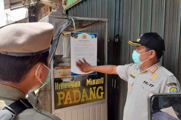 Petugas Satpol PP Kota Serang menempelkan imbauan di salah satu rumah makan, Rabu (14/4/2021).