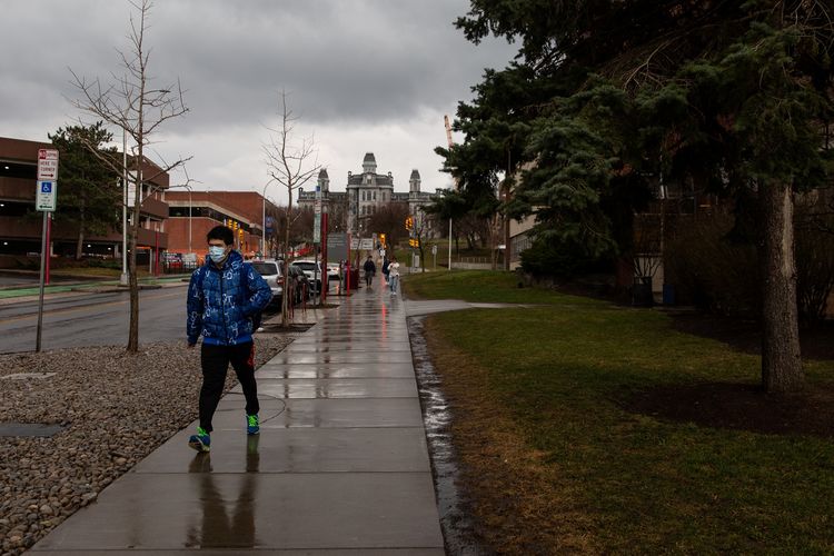 Seorang mahasiswa berjalan memakai masker, sesuai anjuran pemerintah agar tidak tertular virus corona. Gambar diambil di Syracuse University, New York, Amerika Serikat (AS) pada Jumat (13/3/2020).