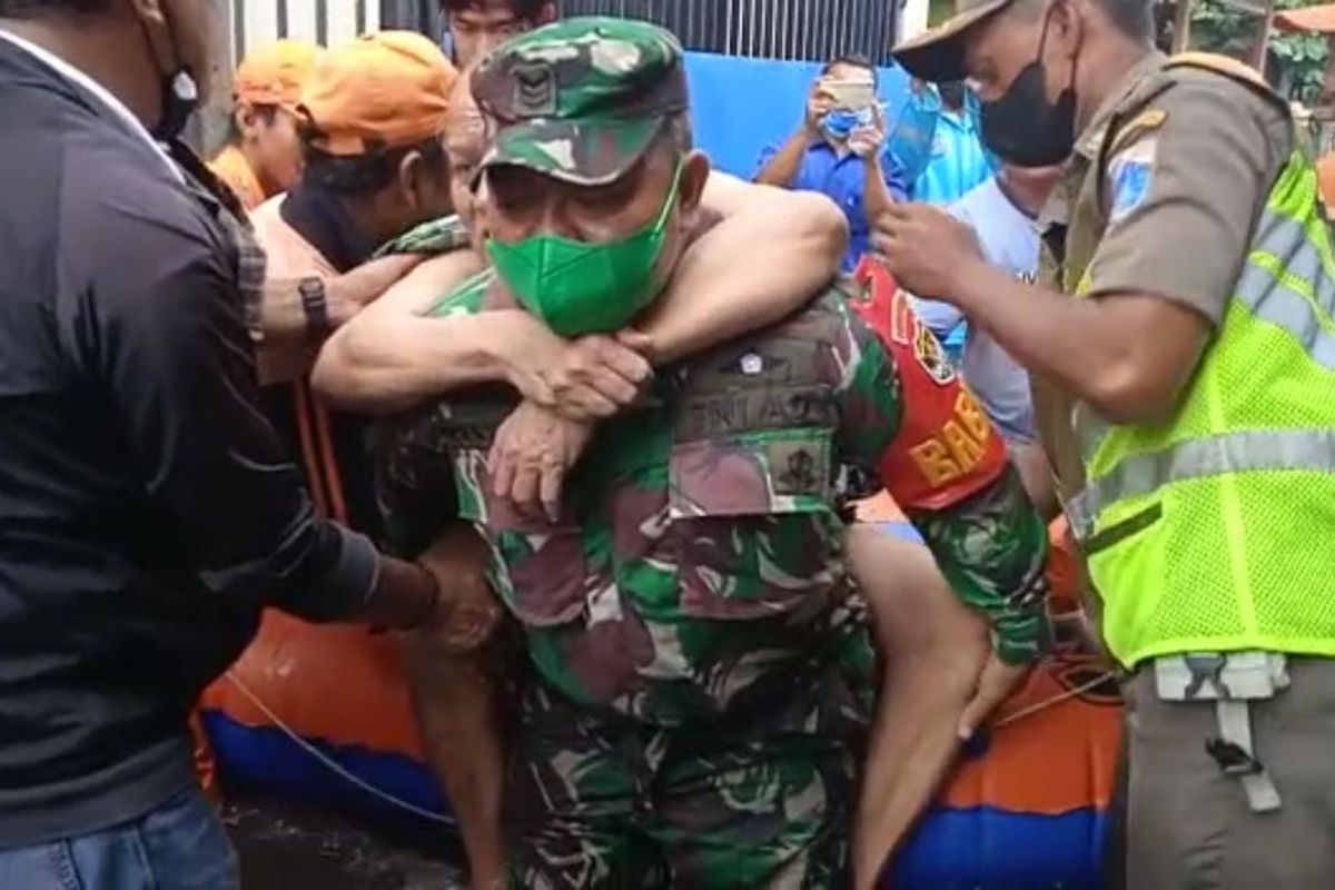 Personel Babinsa Kepala Sersan TNI Kastono menggendong lansia korban banjir rob di RT/11 RW/08 Kelurahan Ancol, Kecamatan Pademangan, Jakarta Utara, Selasa (7/12/2021).