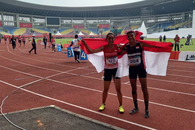 Elvin Elhuida Sesa (kiri) membentangkan bendera Merah Putih bersama Tiwa selepas mendapatkan medali emas dari cabang olahraga para-atletik nomor lati 400 meter T20 putri di Stadion Manahan, Solo, Rabu (3/8/2022) pagi WIB.