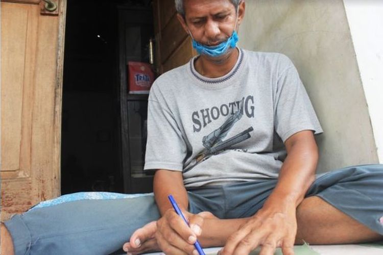 Wabah virus corona memaksa Elfiandi Nain yang bekerja sebagai pekerja harian berhenti bekerja, kini dia membantu istrinya membuat pola masker transparan 